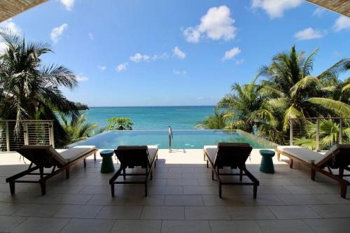 a patio with chairs and a view of the ocean at Wild Serenity's Beach Villa in Castries