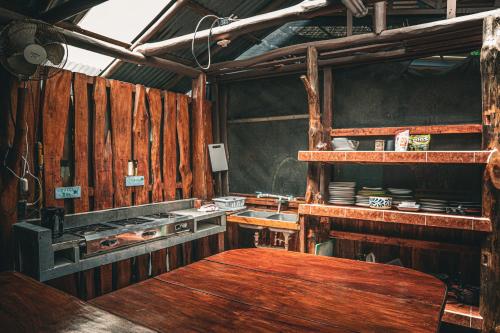 a kitchen with wooden walls and a wooden table at Flutterby House Hostel in Uvita