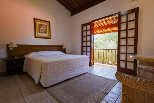 une chambre avec un lit et une porte donnant sur un balcon dans l'établissement Pousada Vale do Dinossauro, à São Pedro