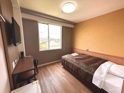 a hotel room with a bed and a desk and a window at Tabist Tsukuba Sky Hotel in Tsukuba