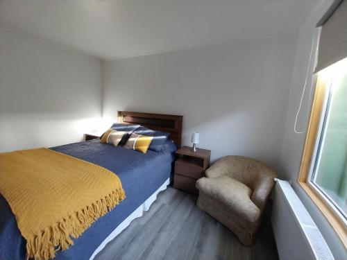 a bedroom with a bed and a chair and a window at Departamento in Punta Arenas