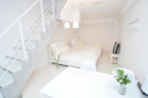 a white room with a bed and a staircase at Bijou Suites Lohas in Osaka