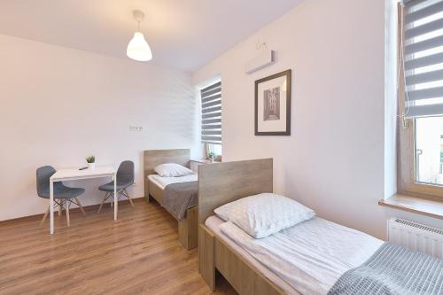 two beds in a room with a desk and a table at Dworcowa 10D in Płock