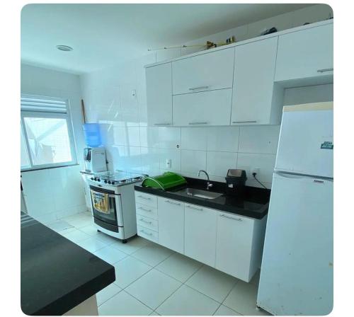 La cuisine blanche est équipée d'un évier et d'un réfrigérateur. dans l'établissement Apartamento canto da Prainha, à Arraial do Cabo