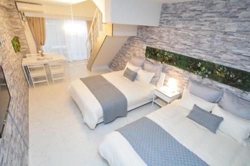 a bedroom with two beds and a stone wall at Bijou Suites Lohas in Osaka