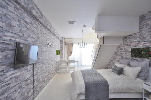 a bedroom with a bed and a brick wall at Bijou Suites Lohas in Osaka