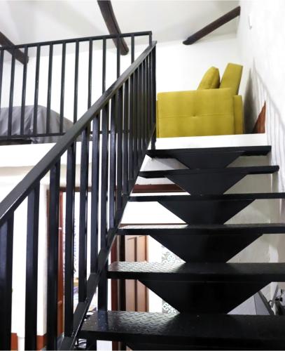 a black staircase with a yellow chair in a room at Hotel Ambar La Morada in Buga