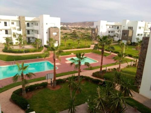 an apartment complex with a swimming pool and palm trees at PERLA SAÏDIA APPART XXL Clima IPTV Piscine Parking Jardin in Saidia 