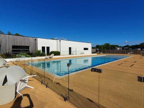 une grande piscine avec des chaises et un bâtiment dans l'établissement Cottage Luxe 3 Chambres, Jacuzzi, Piscine et Parking à 12 km des Sables d'Olonne - FR-1-197-608, à Sainte-Foy