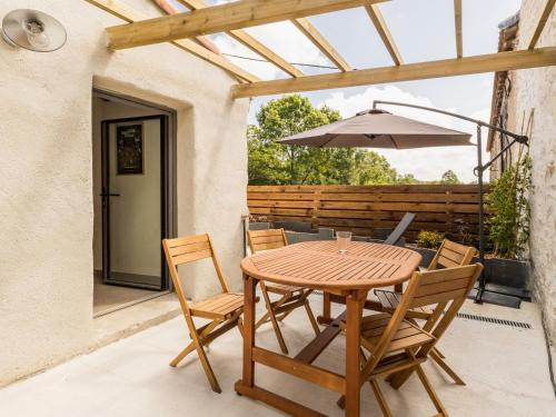 - une table en bois avec des chaises et un parasol sur la terrasse dans l'établissement Ancien corps de ferme rénové avec jardin, proche de Nantes, wifi, borne de recharge et animaux acceptés. - FR-1-306-1280, à Saint-Colombin