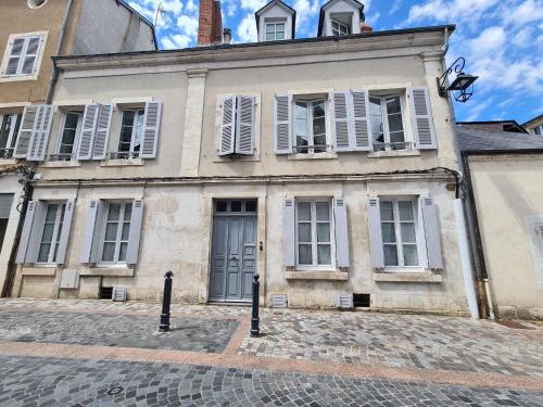 an old building with white shutters on a street at Chambre spacieuse avec grand lit et salle d'eau privée, petit-déjeuner inclus - Châteauroux - FR-1-591-601 in Châteauroux
