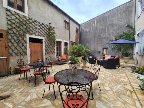a patio with tables and chairs and an umbrella at Chambre chaleureuse "Toscane" avec lit 160cm, salle d'eau privative et petit-déjeuner inclus. - FR-1-591-600 in Châteauroux