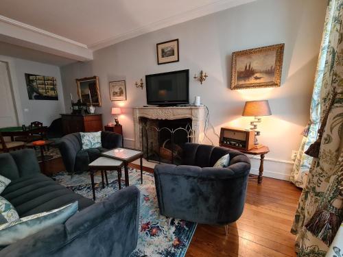 a living room with couches and a television and a fireplace at Chambre spacieuse avec grand lit et salle d'eau privée, petit-déjeuner inclus - Châteauroux - FR-1-591-601 in Châteauroux