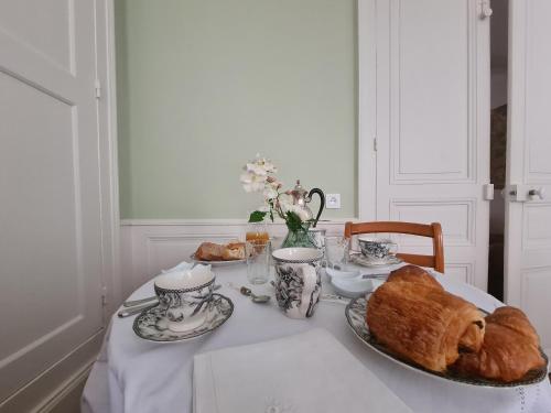 a table with croissants and cups and a plate of bread at Chambre chaleureuse "Toscane" avec lit 160cm, salle d'eau privative et petit-déjeuner inclus. - FR-1-591-600 in Châteauroux