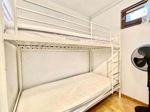 Ce lit superposé blanc se trouve dans un dortoir. dans l'établissement Studio lumineux avec cabine, parking privé, près de la plage - FR-1-338-590, à Sète