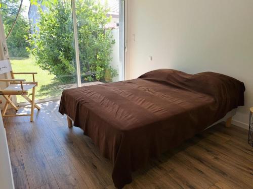 un lit dans une chambre avec une grande fenêtre dans l'établissement Maison de charme avec grand jardin, terrasse et WIFI, proche plage et commerces - FR-1-323-551, à Saint-Hilaire-de-Riez