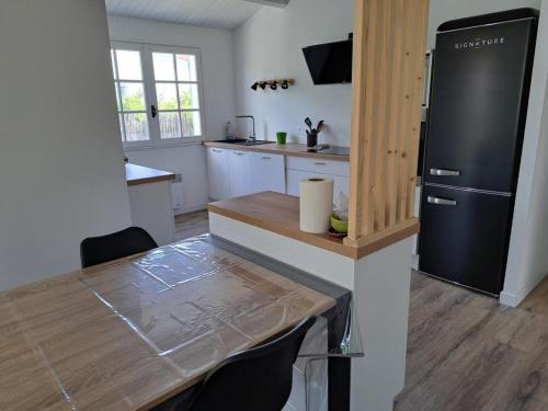 Il comprend une cuisine équipée d'une table et d'un réfrigérateur noir. dans l'établissement Maison de charme avec grand jardin, terrasse et WIFI, proche plage et commerces - FR-1-323-551, à Saint-Hilaire-de-Riez