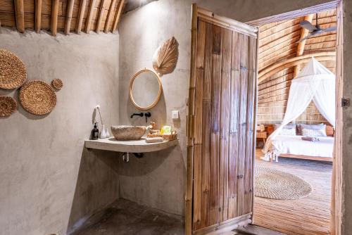 a bathroom with a sink and a mirror and a bed at Luxury Bamboo Villa near Beach in Canggu