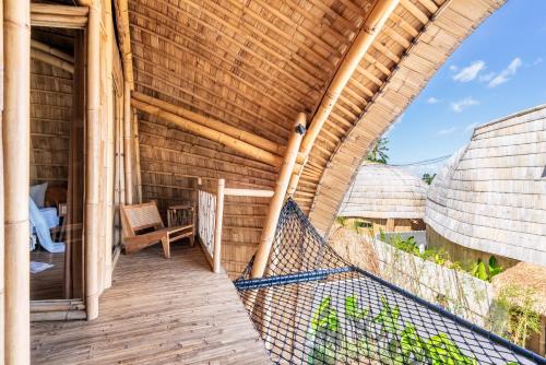 a porch of a wooden house with a chair at Luxury Bamboo Villa near Beach in Canggu