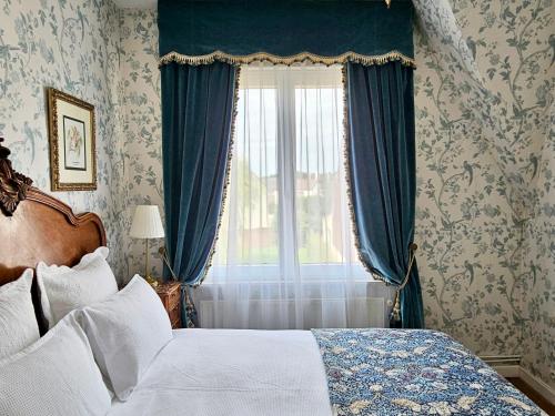 a bedroom with a bed and a window with blue curtains at Maison Trianon 1928 in Quiévrechain