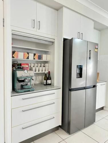 a kitchen with white cabinets and a refrigerator at 7 Bedrooms 20 Mins to City 25 Acres of Green Space in Brisbane