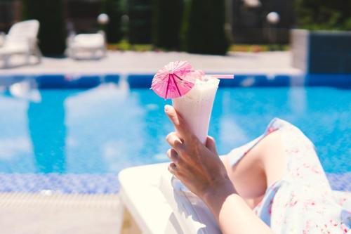una mujer sentada en una piscina sosteniendo una bebida en Арт-отель ololoFamily, en Chon-Sary-Oy