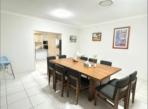 a dining room with a wooden table and chairs at 7 Bedrooms 20 Mins to City 25 Acres of Green Space in Brisbane
