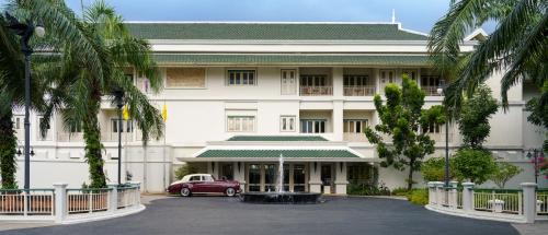 暖武里府Kalanan Riverside Resort的前面有一辆红色汽车的建筑