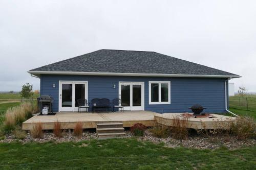 a blue house with a deck in a field at Relaxing Getaway - Fun at the Lake in Pierre