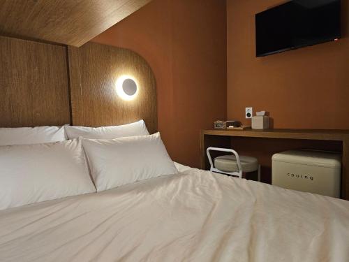 a bedroom with a white bed with a tv on the wall at Huga Inn in Seoul