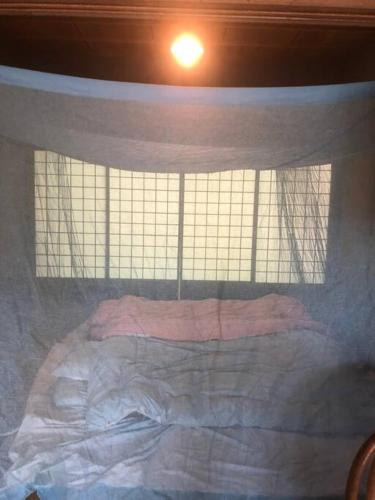 a bed in a room with a window at ゲストハウス+カフェわ　１日１組限定！ 築１００年の農家の古民家で宿泊体験、薪でお風呂沸かせます。焚き火もできます。 in Kannami