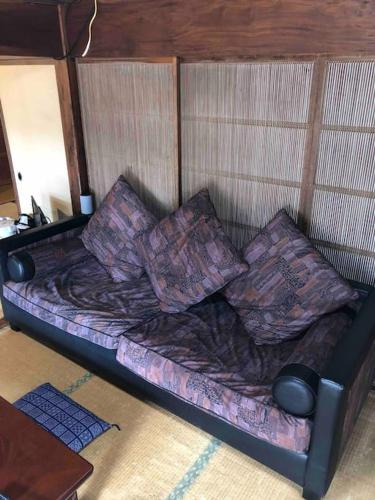 a couch with pillows on it in a room at ゲストハウス+カフェわ　１日１組限定！ 築１００年の農家の古民家で宿泊体験、薪でお風呂沸かせます。焚き火もできます。 in Kannami