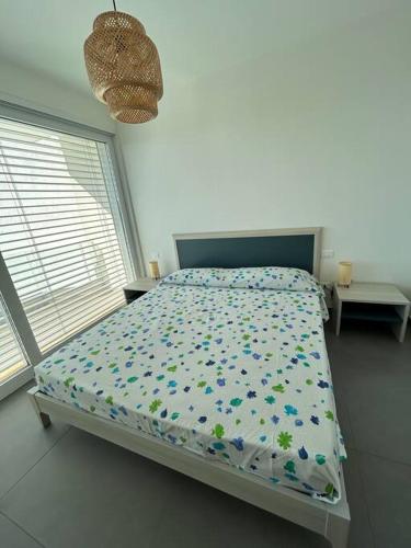 a bedroom with a bed with a floral comforter and a window at Clara Grace sea view in Leuca