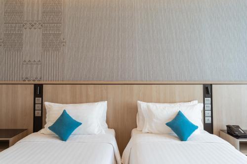 two beds in a hotel room with blue pillows at Centre Point Hotel Terminal21 Korat in Nakhon Ratchasima
