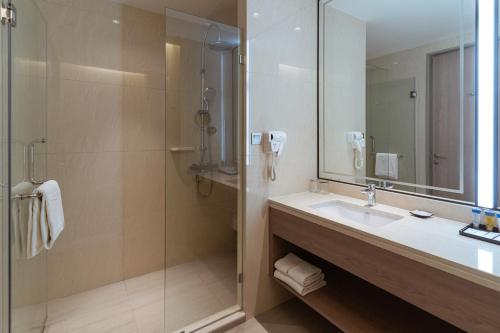 a bathroom with a sink and a shower with a mirror at Centre Point Hotel Terminal21 Korat in Nakhon Ratchasima