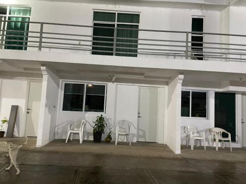 une maison blanche avec des chaises blanches et un balcon dans l'établissement Departamento los pinos 1, à Zurumútaro