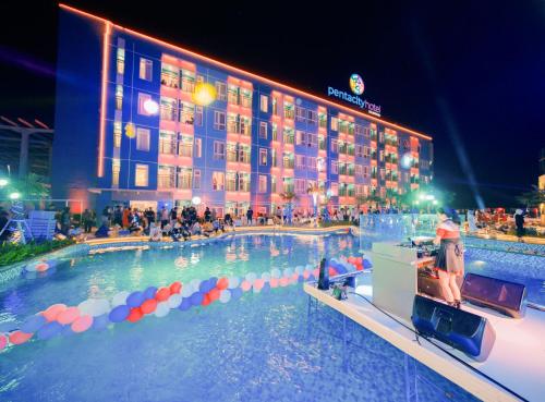 a large swimming pool with a hotel in the background at The All - Suite Pentacity Hotel Balikpapan in Balikpapan
