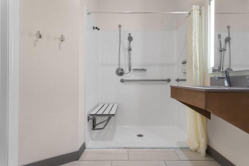 a bathroom with a shower and a bench next to a sink at Candlewood Suites La Crosse by IHG in La Crosse