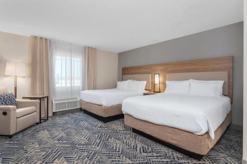 a hotel room with two beds and a chair at Candlewood Suites La Crosse by IHG in La Crosse