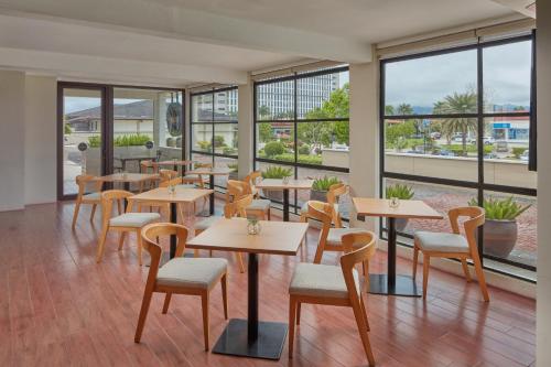 a restaurant with tables and chairs and windows at Holiday Inn & Suites Batangas LimaPark by IHG in Batangas City