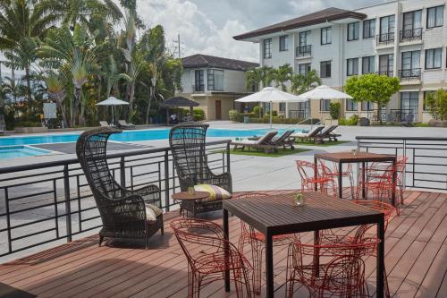 a patio with tables and chairs next to a pool at Holiday Inn & Suites Batangas LimaPark by IHG in Batangas City