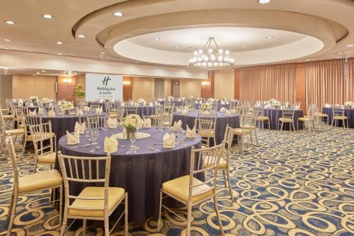 a banquet hall with tables and chairs and a chandelier at Holiday Inn & Suites Batangas LimaPark by IHG in Batangas City