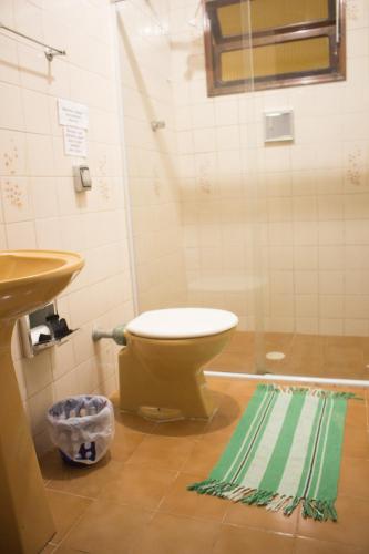 a bathroom with a toilet and a sink and a rug at Casa Trilha Caiçara cuarto privado in Ubatuba