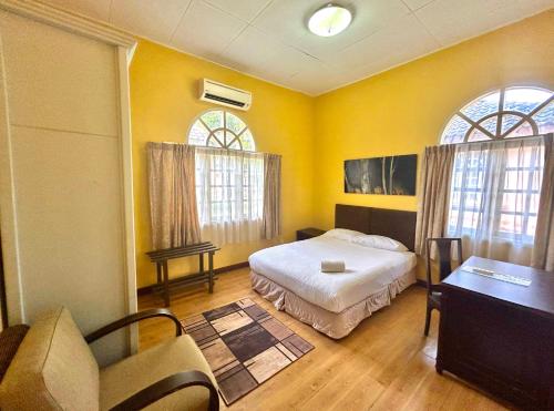 ein Schlafzimmer mit einem Bett und einem Schreibtisch und zwei Fenstern in der Unterkunft RUMBIA RESORT VILLA Paka Terengganu in Paka