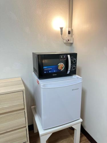 a microwave sitting on top of a refrigerator at Service Apartment ห้อง102 ใจกลางเมืองใกล้แหล่งท่องเที่ยว in Lampang