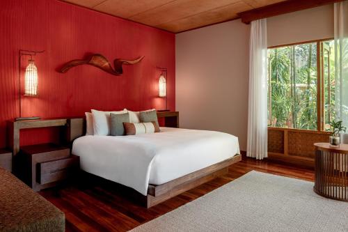 a bedroom with a white bed and a red wall at Anantara Rasananda Koh Phangan Villas in Thong Nai Pan Noi