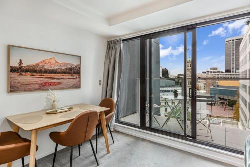 a room with a table and chairs and a large window at Stylish Modern Unit w Balcony and Pool Zodiak Stays in Auckland