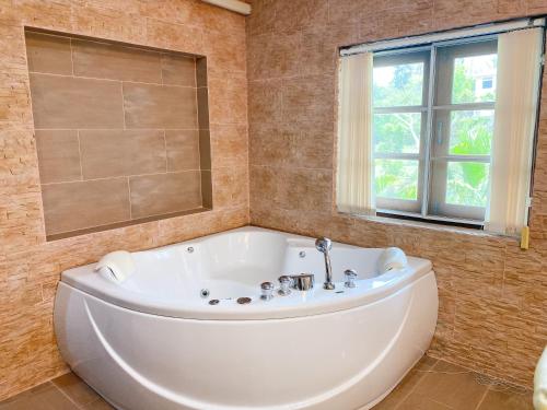 a large white tub in a bathroom with a window at Huahinpoolvilla in Hua Hin