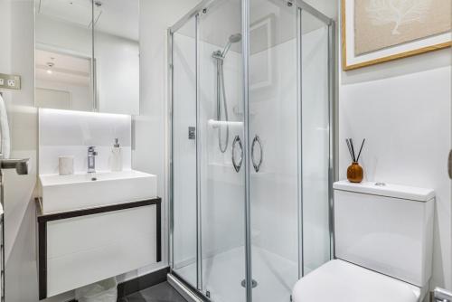 a white bathroom with a shower and a sink at Stylish Modern Unit w Balcony and Pool Zodiak Stays in Auckland
