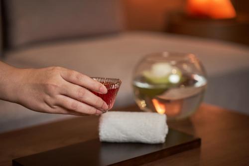 a hand holding a glass of wine on a table at Luxcity Hotel & Apartment in Phnom Penh